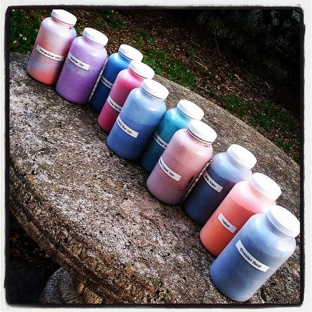 Image: 7 jars of powder coat pigment in red, purple, blue, and orange